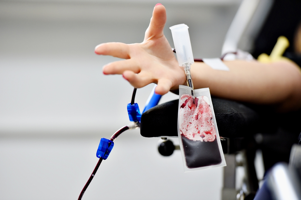 Detail with the hand of a blood donor and a plastic blood bag in a hospital