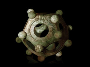 Ancient bronze Roman dodecahedron on a black background