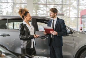 A woman selling a car to a man. 