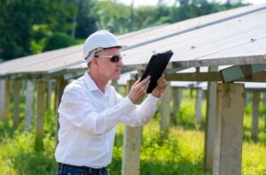 Energy field Engineer using tablet working and checking at solar panels at a plant.