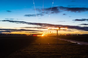 Airport at dusk with landing lights, runway and light traces of an airplane approaching