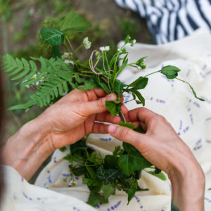 A woman's hands weave a crown made of leaves