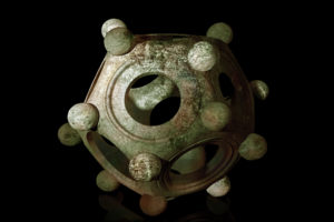 Ancient bronze Roman dodecahedron on a black background
