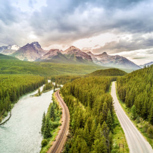 A lake and road in canada with forest surroundings and a view of mountains