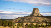 Devils Tower, a flat rocky butte stands tall above the surrounding land.