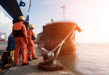 A haulage ship at the port surrounded by construction workers.