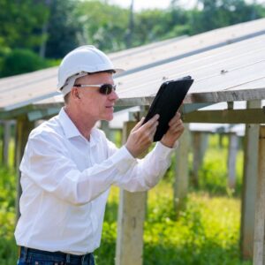 Energy field Engineer using tablet working and checking at solar panels at a plant.
